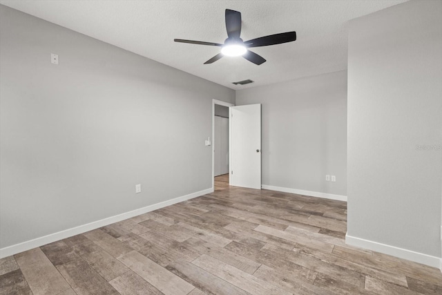 empty room with ceiling fan, a textured ceiling, and light wood-type flooring