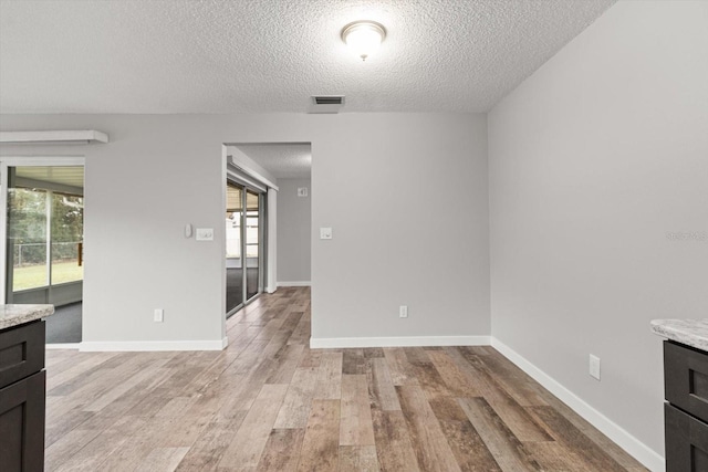 interior space featuring light wood-type flooring and a textured ceiling