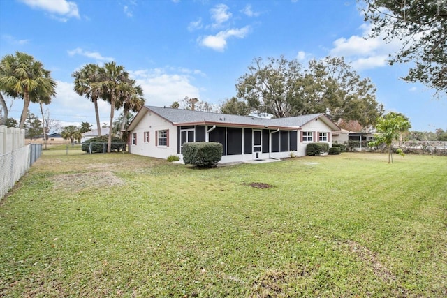 rear view of house featuring a yard and a sunroom