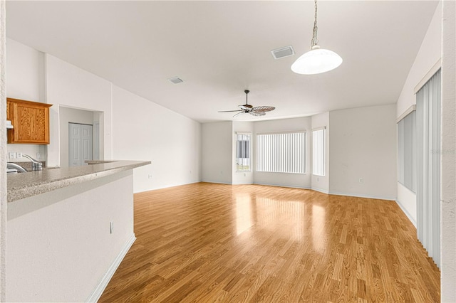 unfurnished living room featuring ceiling fan, sink, and light hardwood / wood-style floors