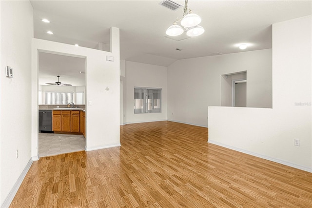 spare room featuring vaulted ceiling, ceiling fan with notable chandelier, sink, and light hardwood / wood-style flooring