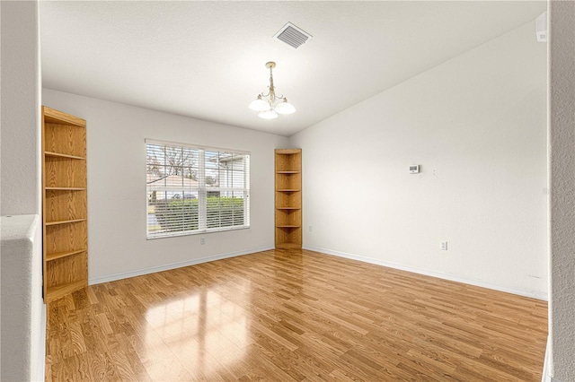 spare room with wood-type flooring and an inviting chandelier