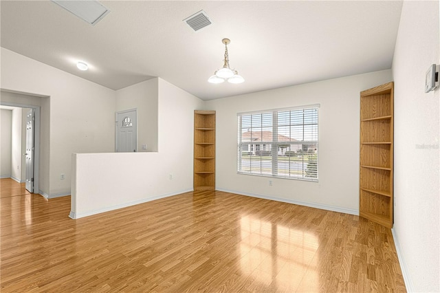 unfurnished room featuring lofted ceiling, hardwood / wood-style floors, and a chandelier