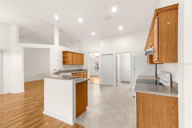 kitchen with sink, range, high vaulted ceiling, and kitchen peninsula