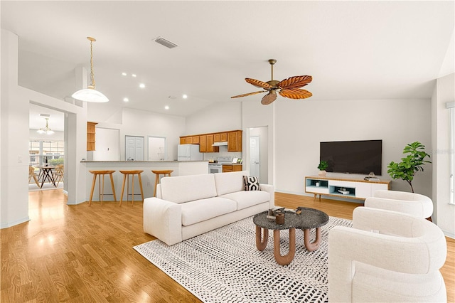 living room with ceiling fan, lofted ceiling, and light hardwood / wood-style floors