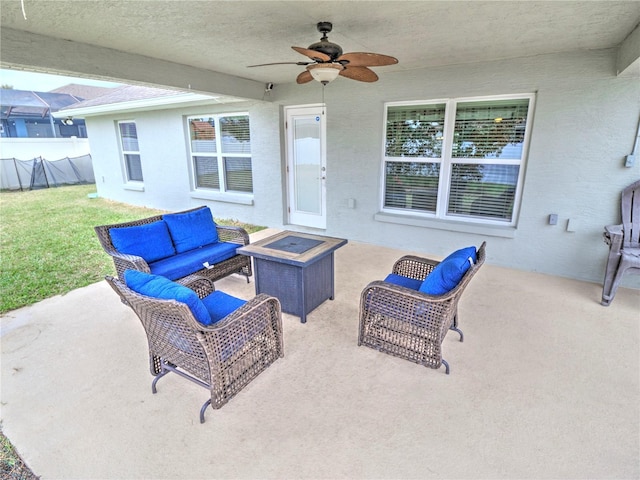 view of patio / terrace featuring ceiling fan and an outdoor living space with a fire pit