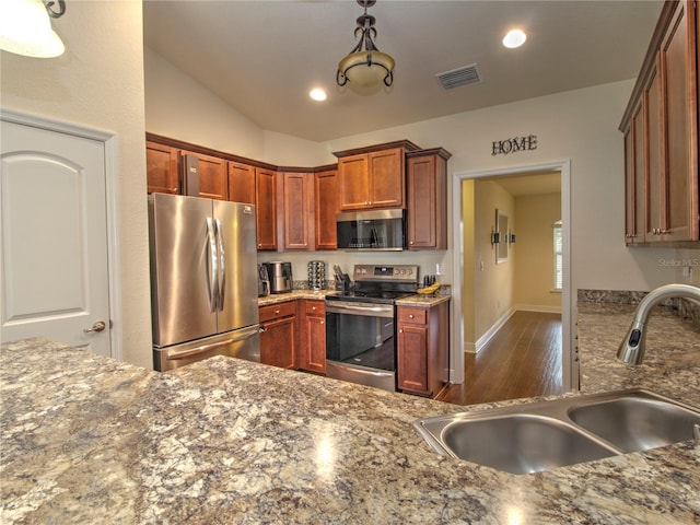 kitchen with appliances with stainless steel finishes, light stone countertops, sink, and hanging light fixtures