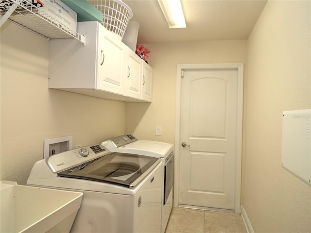 washroom with cabinets, independent washer and dryer, sink, and light tile patterned floors