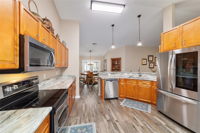 kitchen with hanging light fixtures, appliances with stainless steel finishes, sink, and lofted ceiling