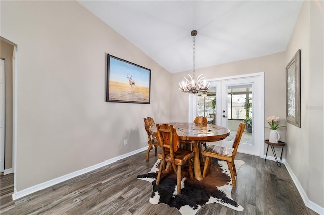 dining space featuring vaulted ceiling, dark wood-type flooring, a notable chandelier, and french doors