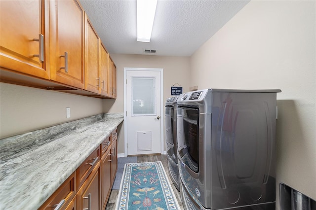 laundry room featuring dark hardwood / wood-style flooring, cabinets, washer and dryer, and a textured ceiling