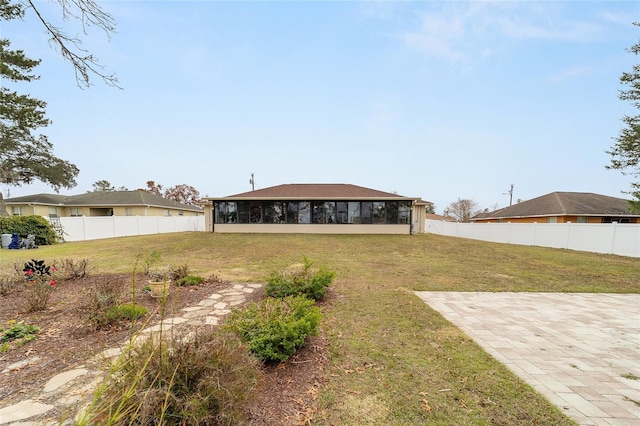 rear view of house featuring a sunroom, a patio area, and a lawn