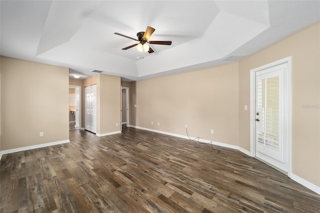 unfurnished living room featuring dark wood-style floors, a raised ceiling, visible vents, and baseboards