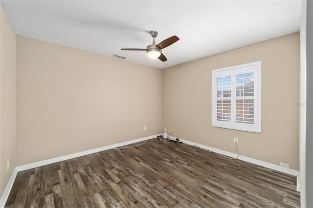 spare room with dark wood-style flooring, visible vents, and baseboards