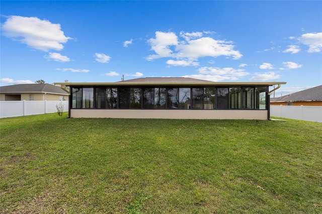 back of property featuring a lawn, a fenced backyard, and a sunroom