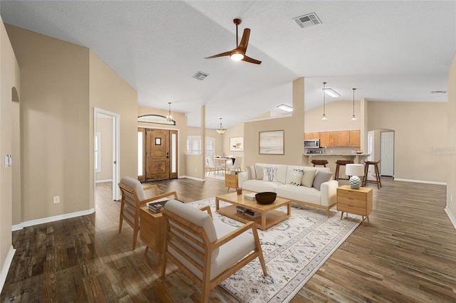 living room featuring dark wood-type flooring, arched walkways, and visible vents