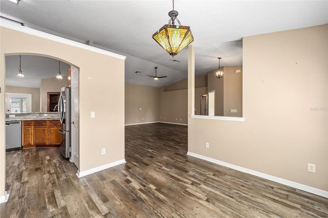 empty room featuring lofted ceiling, baseboards, arched walkways, and dark wood-type flooring