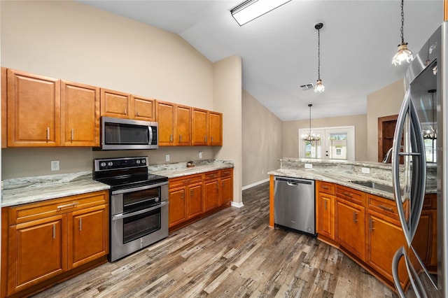 kitchen featuring appliances with stainless steel finishes, brown cabinets, decorative light fixtures, and dark wood-type flooring