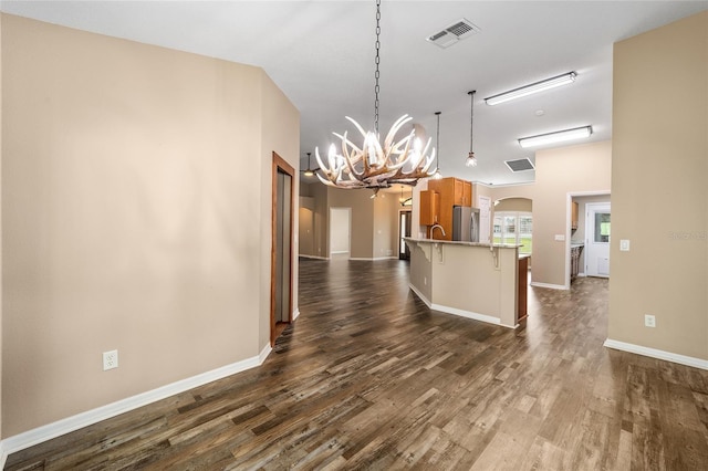 kitchen with arched walkways, a breakfast bar area, visible vents, freestanding refrigerator, and dark wood finished floors