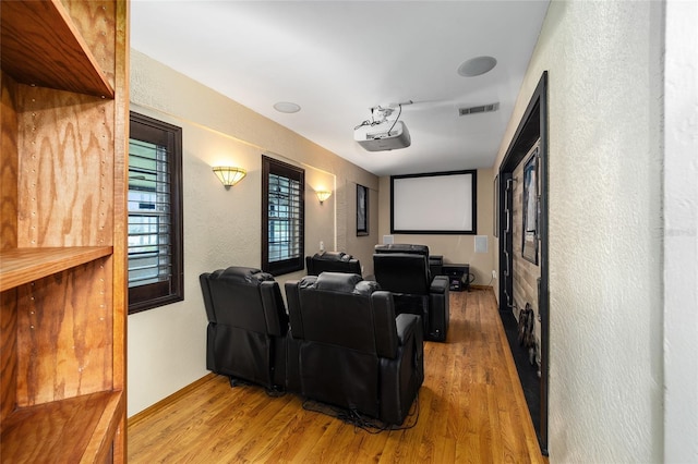 cinema room featuring a textured wall, wood finished floors, and visible vents