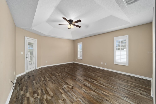 spare room featuring wood finished floors, a raised ceiling, visible vents, and a healthy amount of sunlight