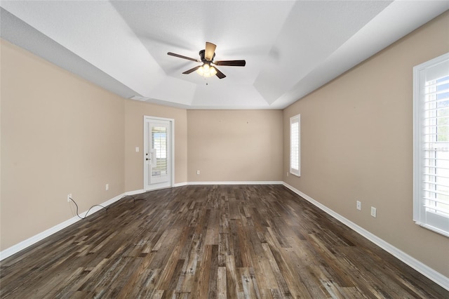 empty room with plenty of natural light, baseboards, and a raised ceiling