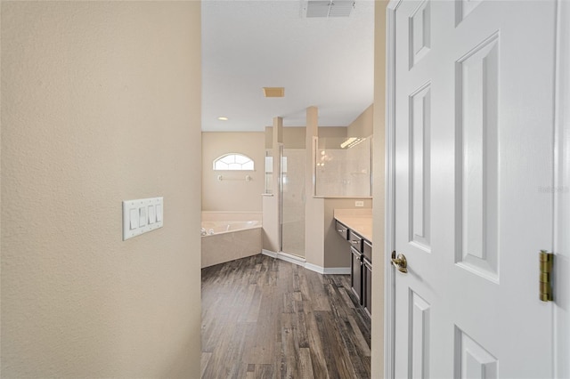 bathroom with a garden tub, wood finished floors, vanity, visible vents, and a stall shower