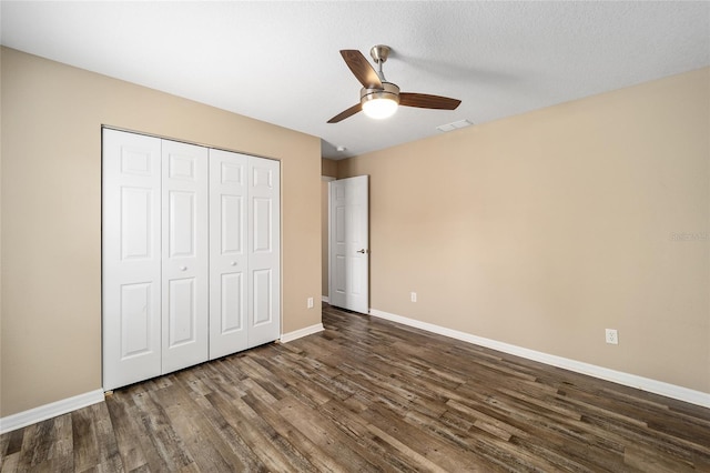 unfurnished bedroom with a ceiling fan, visible vents, baseboards, a closet, and dark wood finished floors