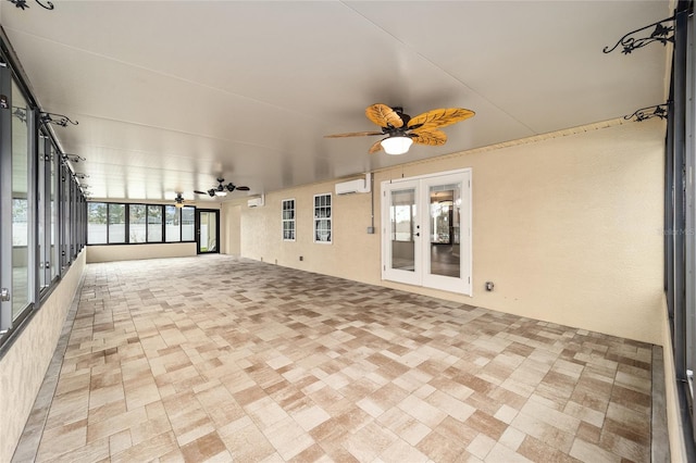 unfurnished sunroom featuring a ceiling fan, an AC wall unit, and french doors