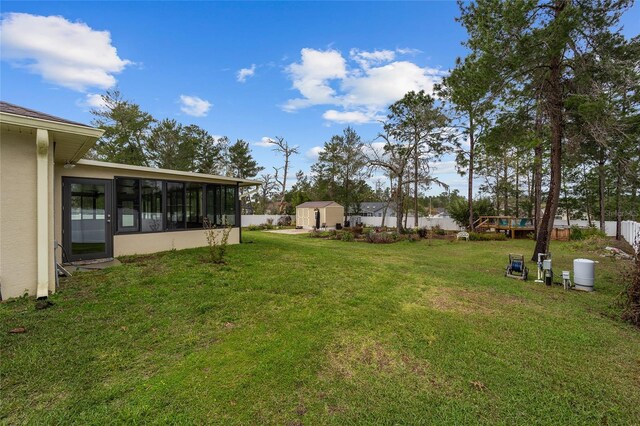 view of yard with an outbuilding, a sunroom, fence, and a storage shed