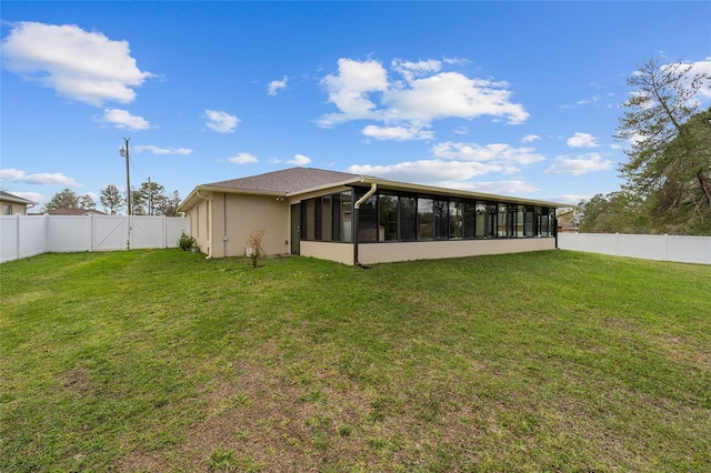 back of property featuring a sunroom, a fenced backyard, and a lawn