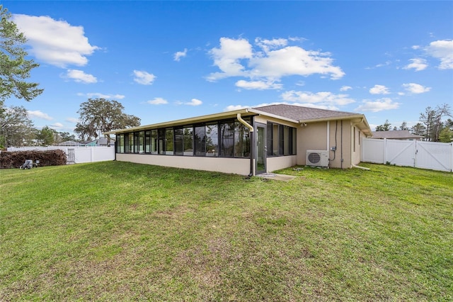 rear view of property with ac unit, a lawn, a sunroom, a gate, and a fenced backyard