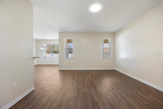 unfurnished room with dark wood-type flooring and a chandelier