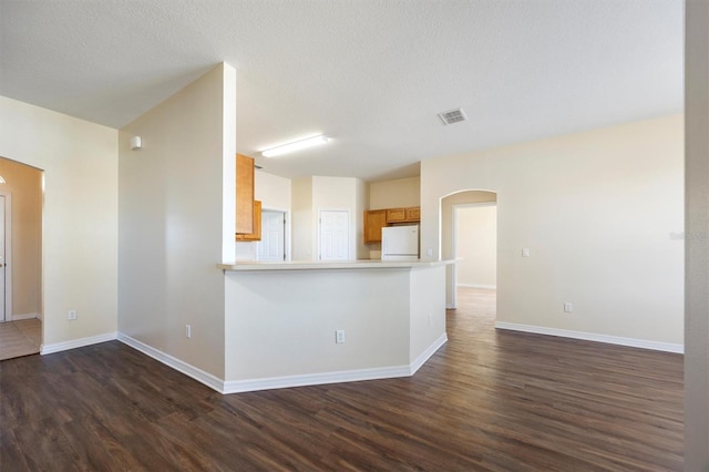 kitchen with white refrigerator, dark hardwood / wood-style floors, a textured ceiling, and kitchen peninsula