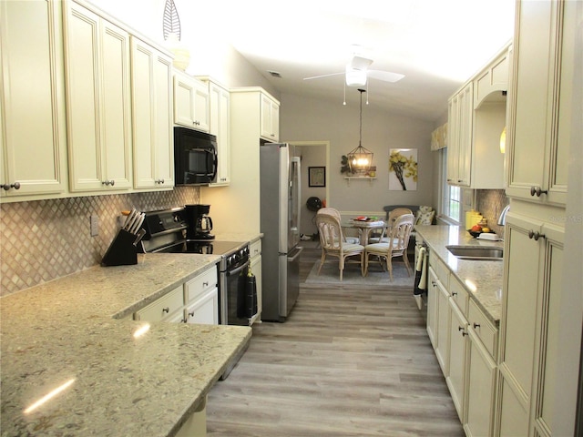 kitchen featuring electric range oven, freestanding refrigerator, black microwave, pendant lighting, and a sink