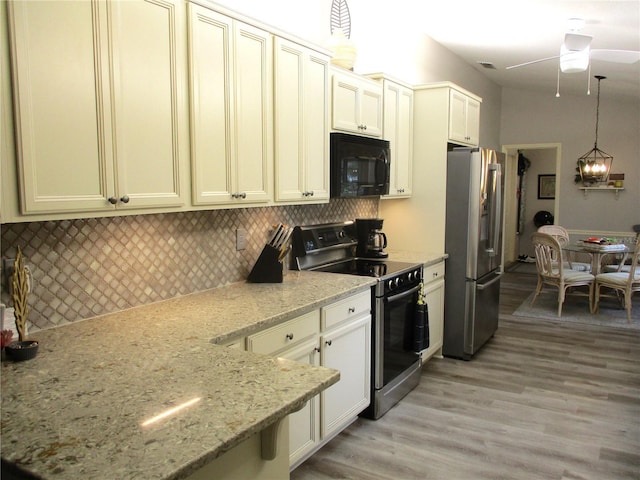 kitchen featuring decorative backsplash, light wood-style flooring, appliances with stainless steel finishes, light stone counters, and pendant lighting