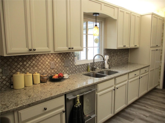 kitchen featuring dishwasher, cream cabinets, a sink, and light stone countertops