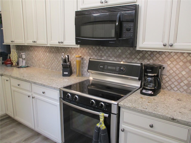 kitchen with electric stove, black microwave, light stone counters, and tasteful backsplash