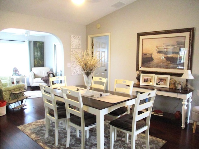 dining space with arched walkways, lofted ceiling, visible vents, a ceiling fan, and dark wood finished floors