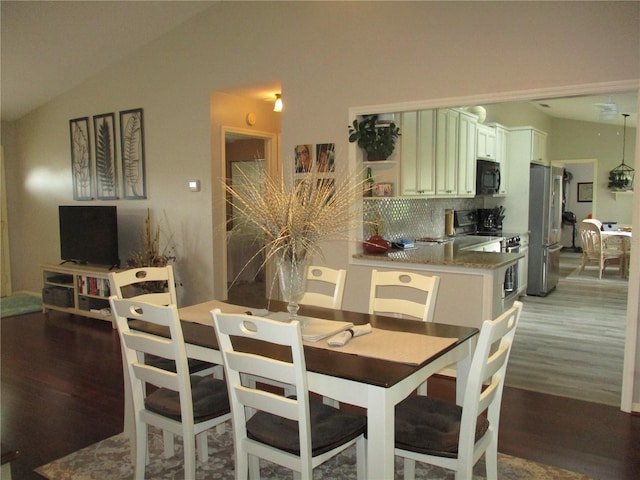 dining space featuring vaulted ceiling and wood finished floors