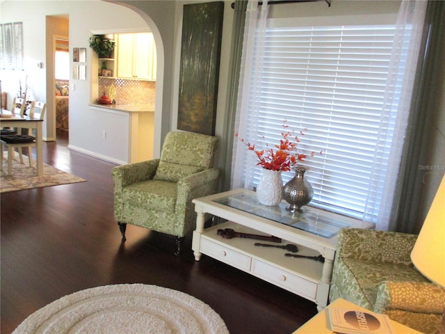 living area featuring arched walkways and dark wood finished floors