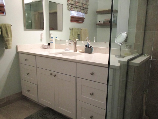 full bathroom with vanity, baseboards, tiled shower, and tile patterned floors