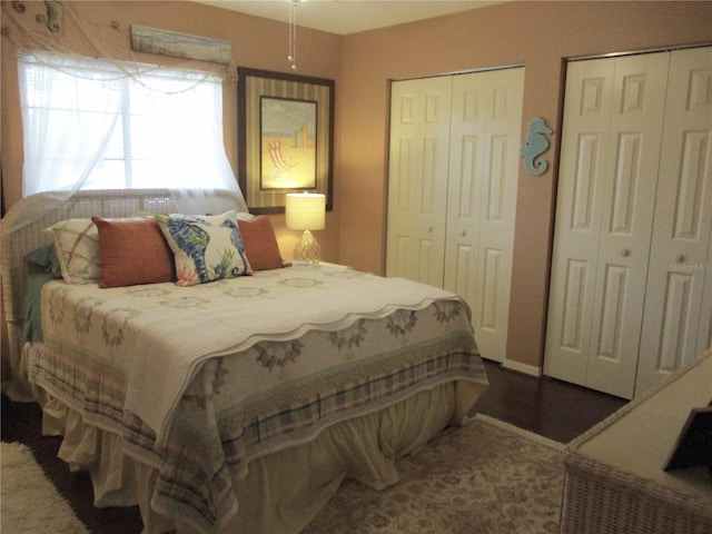 bedroom with dark wood-style floors and two closets