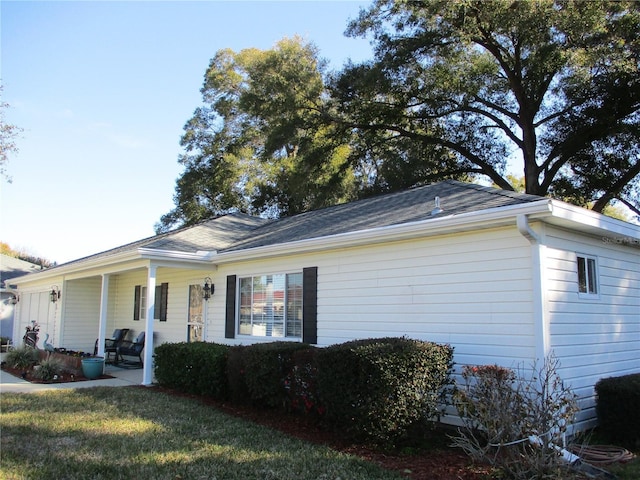 view of side of home with covered porch and a yard