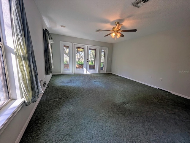 spare room with dark colored carpet, a healthy amount of sunlight, ceiling fan, and french doors