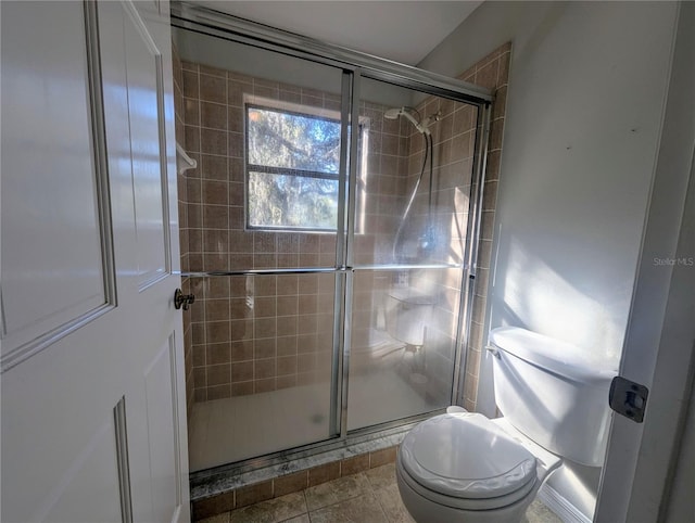 bathroom with an enclosed shower, tile patterned floors, and toilet