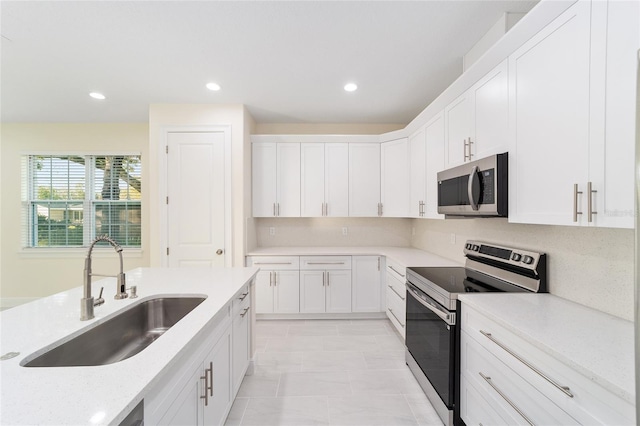 kitchen with light tile patterned flooring, sink, light stone counters, white cabinetry, and stainless steel appliances