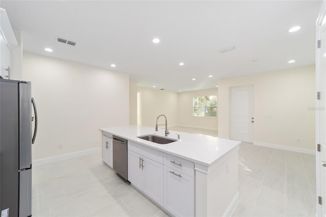 kitchen featuring light tile patterned flooring, sink, white cabinetry, stainless steel appliances, and a kitchen island with sink