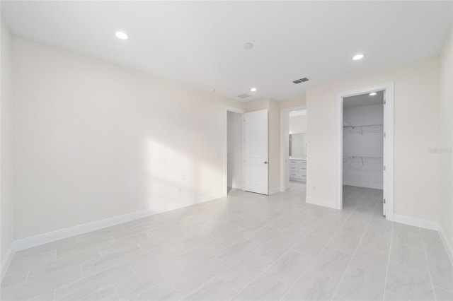 unfurnished bedroom featuring a spacious closet, light tile patterned floors, and a closet