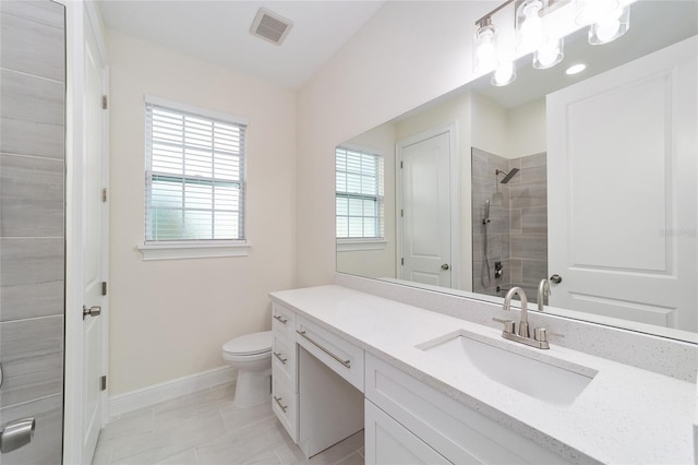 bathroom with vanity, toilet, tile patterned flooring, and a tile shower